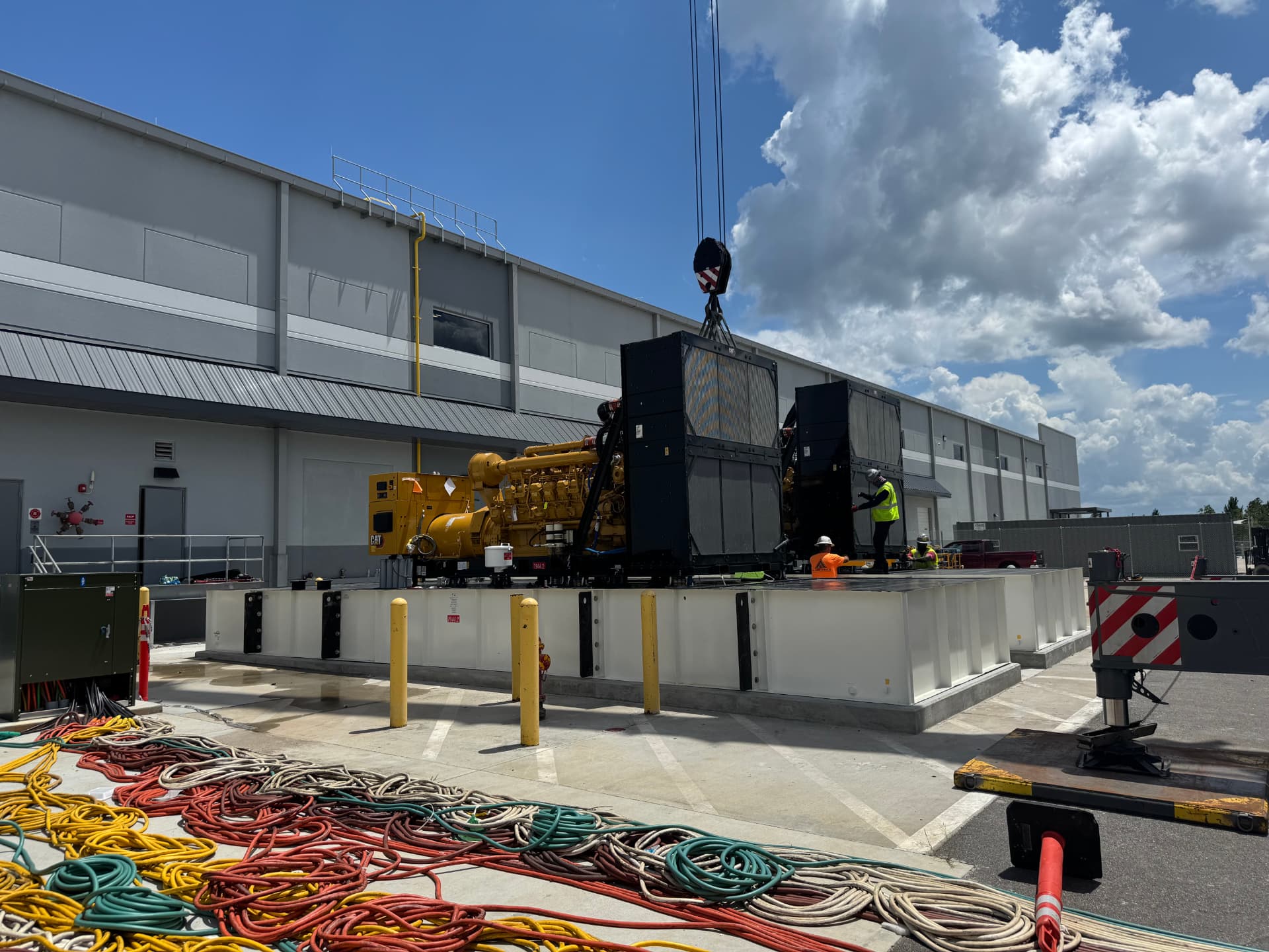 Crane setting a standby generator at an industrial site
